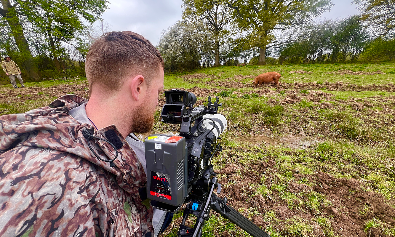 boy with camera and pig in the distance